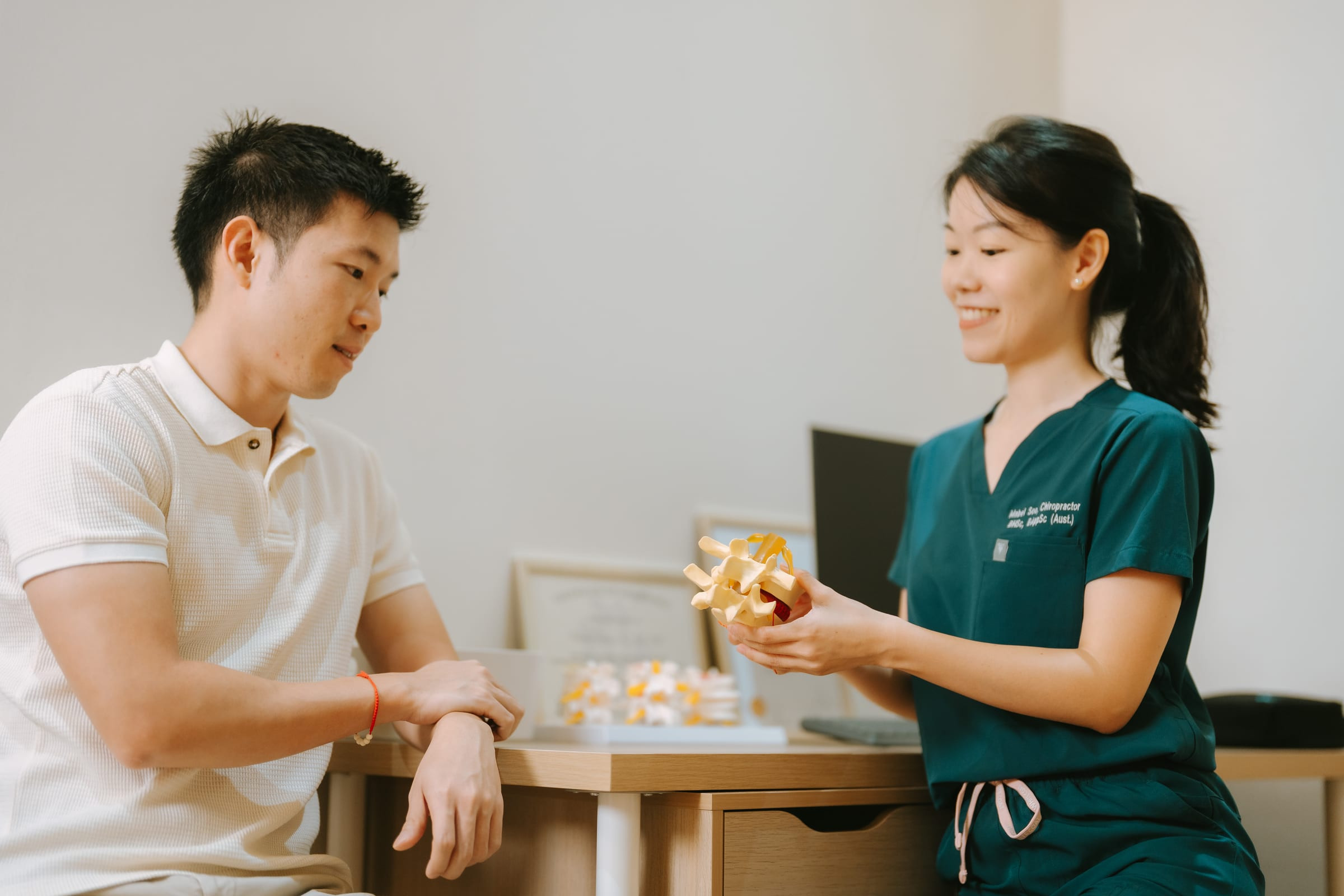 Chiropractor assessing a male patient with neck pain and headaches